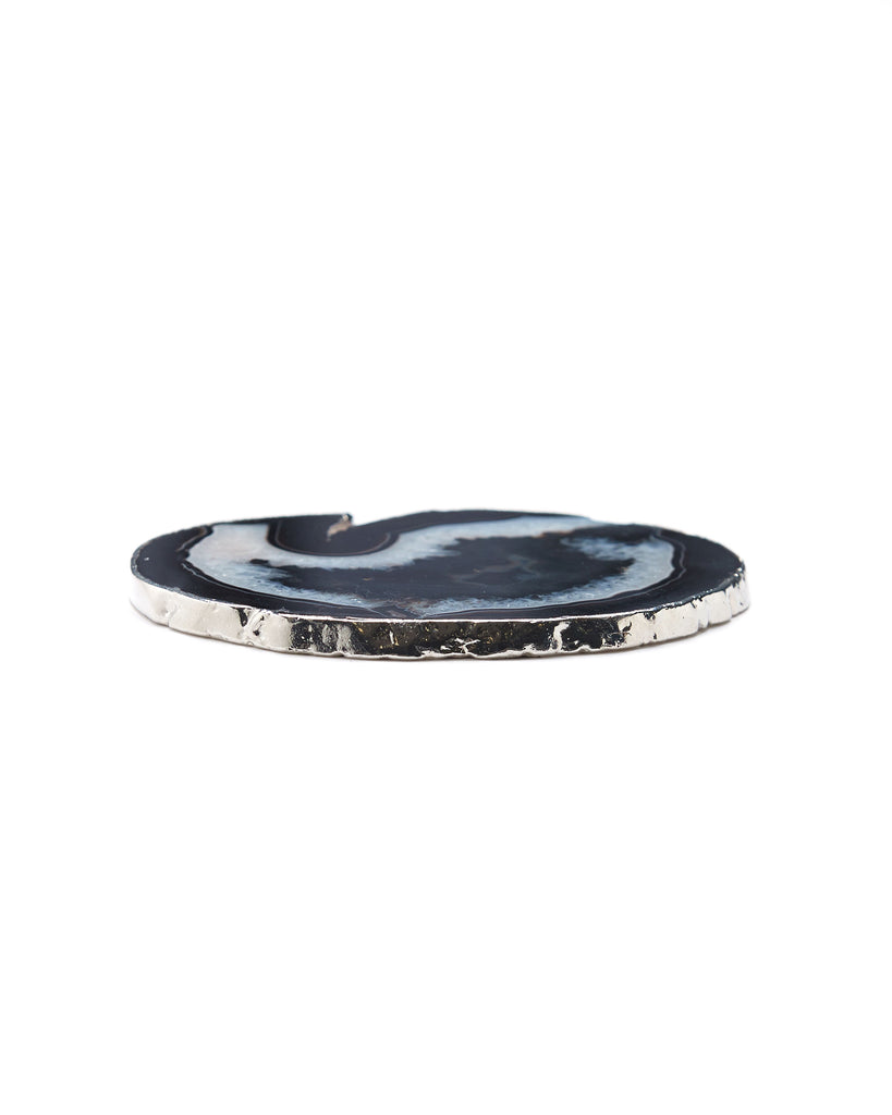 Silver plated black agate crystal coaster. Our natural crystal coasters are the perfect addition to your dining room or coffee table. With natural black agate from Brazil, coated in silver plating, this coaster is an easy way to elevate the luxury in your home.  Black Agate Crystal  80-120mm  Silver Plating  Please note: Due to our crystals being 100% natural, shape and colour patterns will vary.