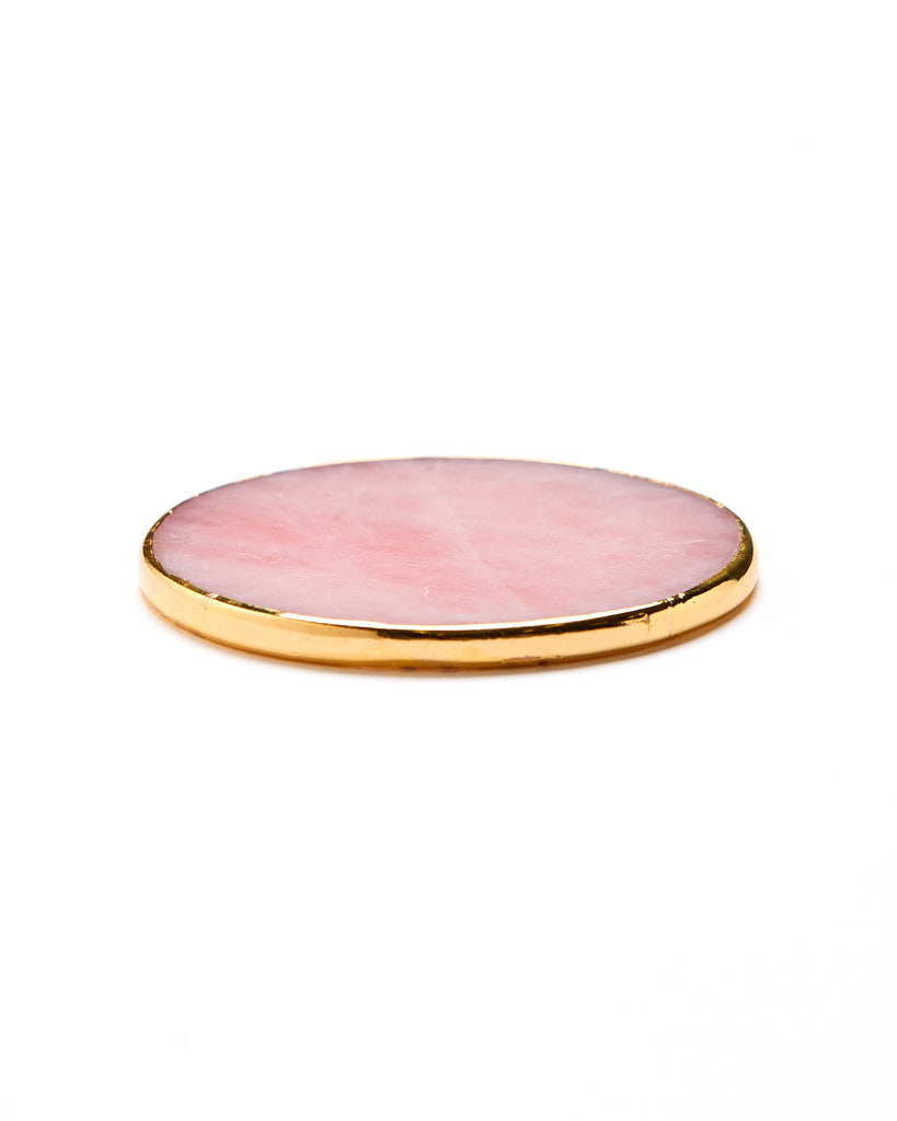 Gold plated rose quartz crystal coaster. Our natural crystal coasters are the perfect addition to your dining room or coffee table. With natural Rose Quartz, coated in yellow gold plating, this coaster is an easy way to elevate the luxury in your home.  Rose Quartz Crystal  80-120mm  Yellow Gold Plating  Please note: Due to our crystals being 100% natural, shape and colour patterns will vary.