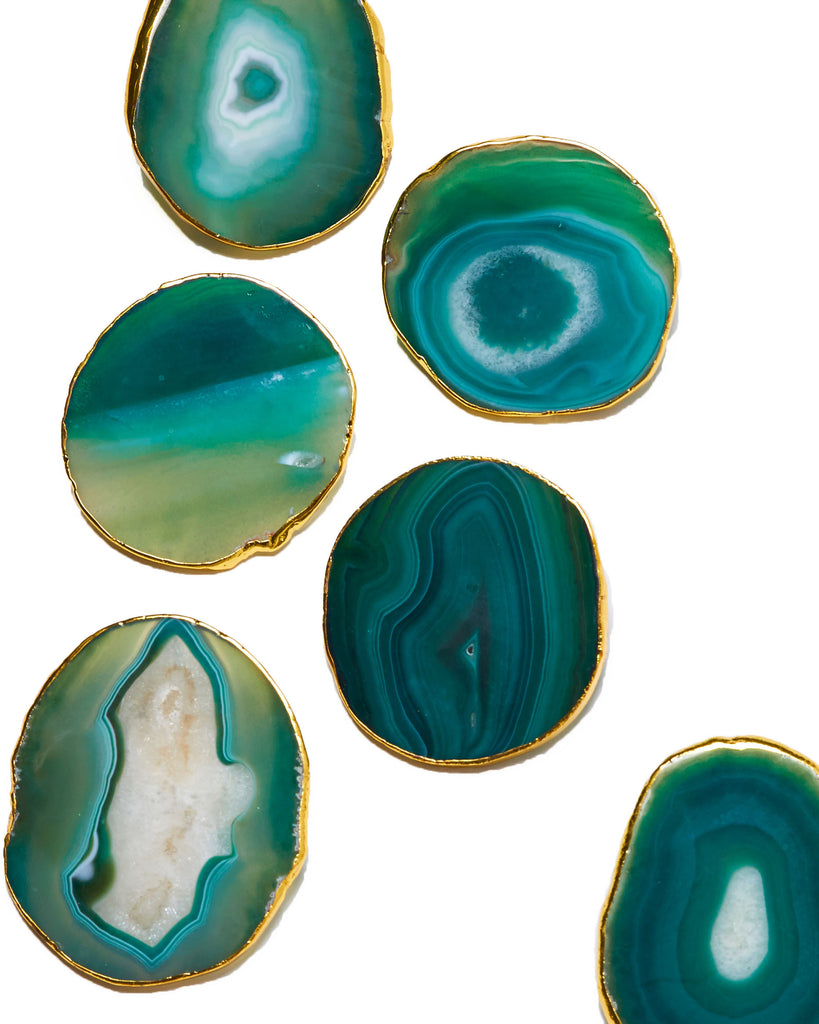 Gold plated green agate crystal coaster. Our natural crystal coasters are the perfect addition to your dining room or coffee table. With natural green agate from Brazil, coated in yellow gold plating, this coaster is an easy way to elevate the luxury in your home.   Green Agate Crystal   80-120mm   Yellow Gold Plating  Please note: Due to our crystals being 100% natural, shape and colour patterns will vary.   