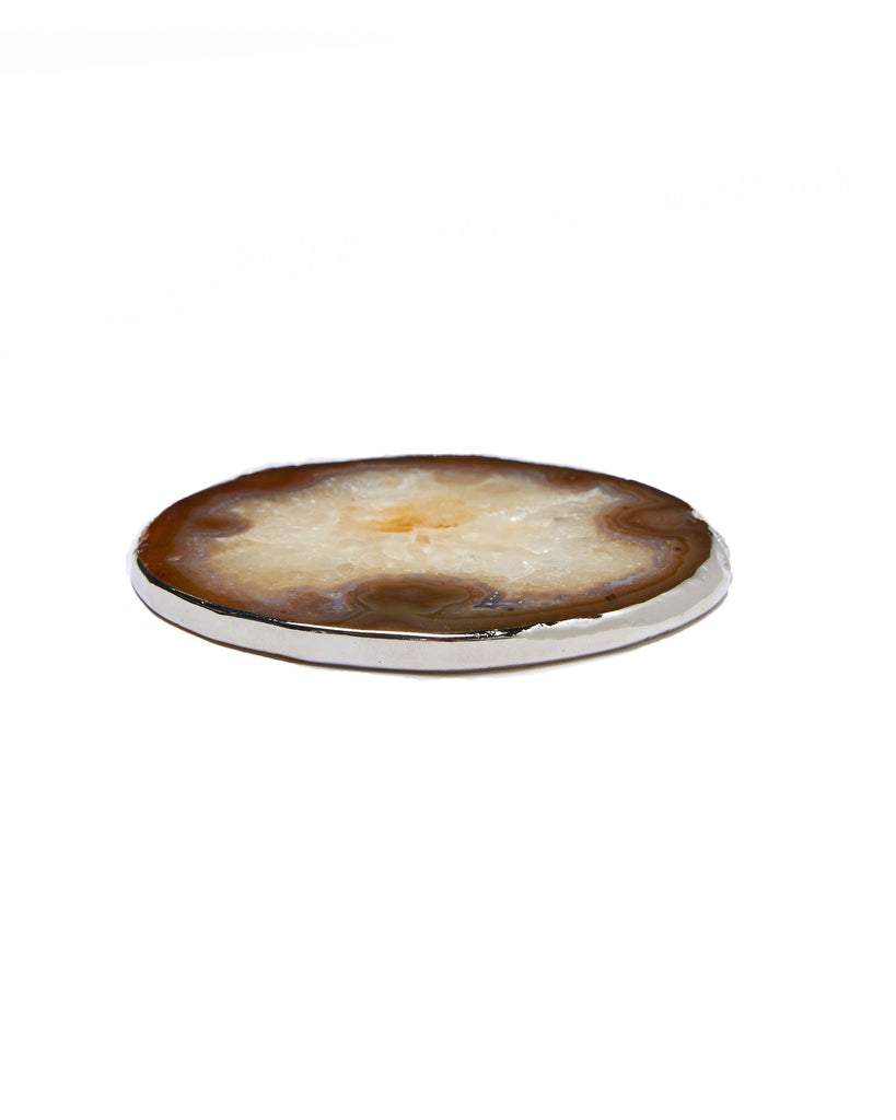 Silver plated amber agate crystal coaster. Our natural crystal coasters are the perfect addition to your dining room or coffee table. With natural amber agate, coated in silver plating, this coaster is an easy way to elevate the luxury in your home.  Amber Agate Crystal  80-120 mm  Silver Plating  Please note: Due to our crystals being 100% natural, shape and colour patterns will vary.